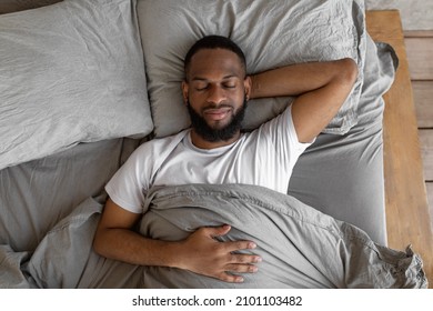 Healthy Sleeping Concept. Above Top View Portrait Of Happy Young Well-slept African American Man Lying On Back In Bed With Closed Eyes, Resting In Bedroom In The Morning, Having Hap