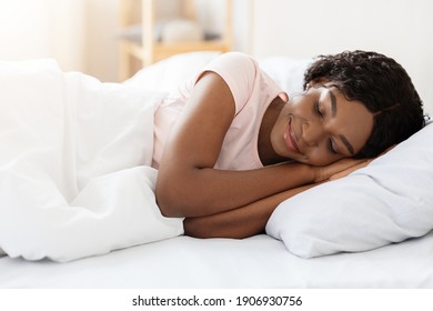 Healthy Sleeping, Sleep Hygiene Concept. Smiling Pretty Young Black Woman Sleeping In Her Bed At Home, Copy Space. African American Lady Having Nap, Resting In White Cozy Bedroom