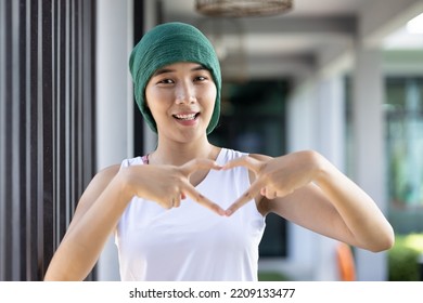 Healthy Smiling Asian Woman Cancer Patient Wearing Head Scarf For Hair Loss After Chemotherapy And Radiation Therapy Giving Heart Hand Gesture For Breast Or Cervical Cancer Awareness Month