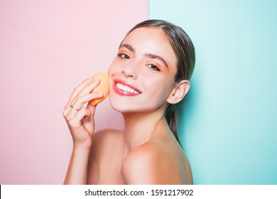 Healthy Smiling Girl With Bare Shoulders, Clear Skin, Dark Hair And Beige Sponge. Natural Makeup Look. Health And Beauty Concept. Happy Young Woman Covering Her Skin With Foundation