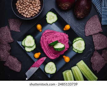 Healthy snack of beet hummus, cucumbers and blue corn chips with the ingredients show cased on the side, whole beets and chick peas. - Powered by Shutterstock