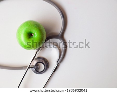 Healthy snack with doctor table. Close up Green apple with Stethoscope for diet an be healthy on white table working and white wooden background. Healthy in Hospital concept.