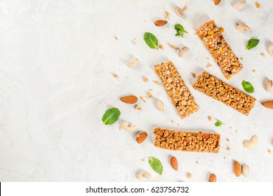 Healthy snack. Fitness. Dietary food. Four cereal granola bars with nuts and fruit berries, with ingredients on a white stone table. Top view copy space