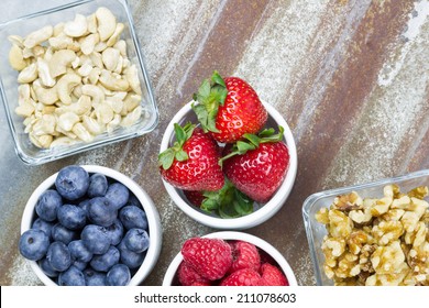 Healthy Snack Foods With Small Bowls Of Raspberries, Blueberries, Strawberries, Cashews And Walnuts