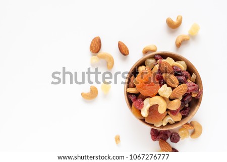 healthy snack: mixed nuts and dried fruits in wooden bowl on white background, almond, pineapple, cranberry, papaya, apple, strawberry, cherry, apricot, cashew.