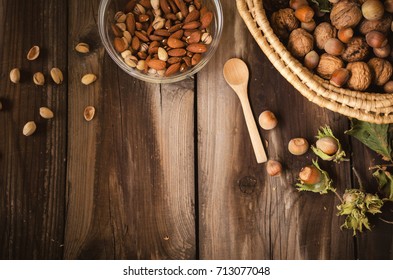Healthy snack on rustic table indoors on autumn. Almonds and pistachio in bowl.