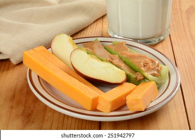 A Healthy Snack Plate With Apple Slices, Cheddar Cheese Sticks And Celery Stuffed With Peanut Butter