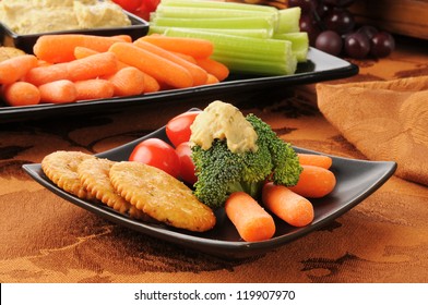 A Healthy Snack Plate With Crackers, Broccoli, Carrots, And Greek Style Hummus