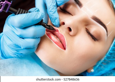 Healthy Spa: Young Beautiful Woman Having Permanent Make-up Tattoo on her Lips. Close-up