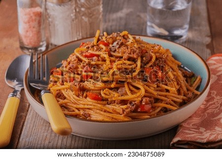 Healthy spaghetti bolognese garnished with seasoning and herbs.