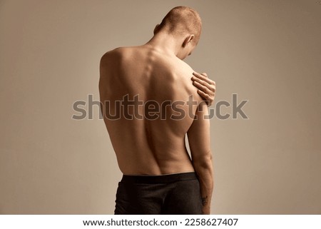 Healthy spine. Image of male strong, relieve, muscular back over grey background. Young model posing in underwear. Concept of men's health and beauty, body and skin care, fitness. Body art