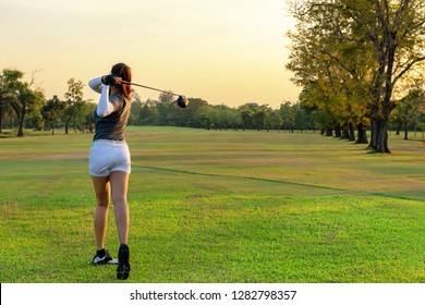 Healthy Sport. Asian Sporty woman golfer player doing golf swing tee off on the green outdoors evening time, she presumably does exercise.  Healthy Lifestyle Concept. - Powered by Shutterstock