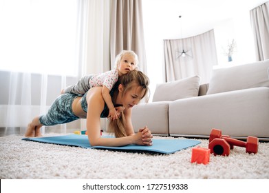 Healthy And Sporty Lifestyle. Young Beautiful Mom In Sportswear Plays Sports At Home With Her Little Daughter. Useful Leisure With A Child At Home