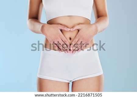Healthy stomach, heart and woman hands, wellness and gut health, body contouring and diet on studio blue background. Fitness model belly love, digestion and skincare, laser liposuction and abdomen