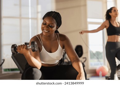 Healthy strong female African American plus-size holding dumbbells lifts weights exercise in gym. sport training weights fitness, Exercise to lose weight, take care of health. - Powered by Shutterstock