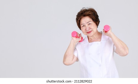 Healthy And Strong Senior Woman Happy And Enjoy Sport Exercise By Lifting Up Dumbbells To Stretch Arm Muscles And Calorie Burnout. Joyful Aunt Warming Up For Lively Workout To Win Athlete Competition.