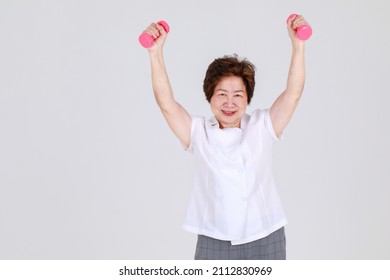 Healthy And Strong Senior Woman Happy And Enjoy Sport Exercise By Lifting Up Dumbbells To Stretch Arm Muscles And Calorie Burnout. Joyful Aunt Warming Up For Lively Workout To Win Athlete Competition.