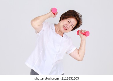 Healthy And Strong Senior Woman Happy And Enjoy Sport Exercise By Lifting Up Dumbbells To Stretch Arm Muscles And Calorie Burnout. Joyful Aunt Warming Up For Lively Workout To Win Athlete Competition.