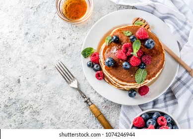 Healthy summer breakfast,homemade classic american pancakes with fresh berry and honey, morning light grey stone background copy space top view