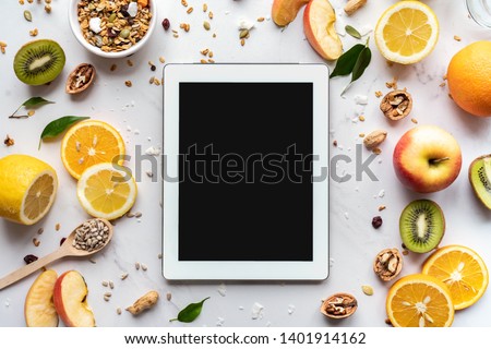Healthy super food and technology background, digital tablet computer apps for cooking diet nutrition plan, fresh fruit granola seeds on white organic table, health care detox, top view mockup screen