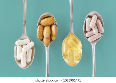 Healthy supplements on teaspoons against colorful background
