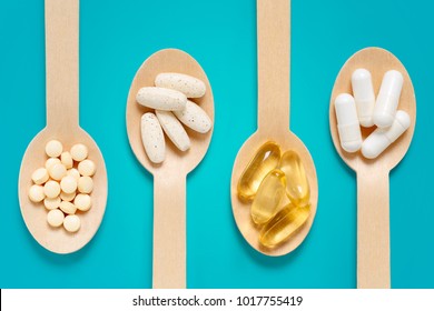 Healthy supplements on wooden teaspoons against pastel blue background - Shutterstock ID 1017755419