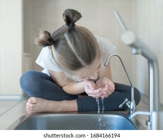 Healthy Thirsty Caucasian Child Drinking From Water Tap Or Faucet In Kitchen. Hands Open For Drinking Tap Water. Pouring Clean Fresh Drink. Concept Of Healthy Lifestyle. Good Habits. World Water Day