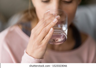Healthy thirsty young woman holding glass in hand drinking fresh clean pure mineral water at home, dehydrated girl keep hydration balance for body health beauty, hydrate thirst concept, close up view