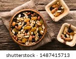 Healthy trail mix snack made of nuts (walnut, almond, peanut) and dried fruits (raisin, sultana) in wooden bowl, photographed overhead (Selective Focus, Focus on the trail mix in the big bowl)