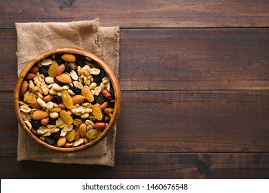 Healthy Trail Mix Snack Made Of Nuts (walnut, Almond, Peanut) And Dried Fruits (raisin, Sultana) In Wooden Bowl, Photographed Overhead With Copy Space On The Right Side