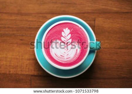 Healthy trendy beetroot latte with latte art in ceramic cup on wooden table. Top view.