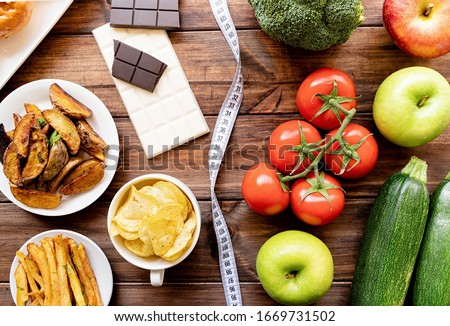 Healthy and unhealthy food concept. Fruit and vegetables vs sweet and potatoe fries top view flat lay on rustic background