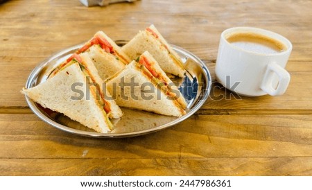 Healthy veg sandwich on wooden board with tea. Delicious vegetarian bread sandwich with herbs, onion, tomatoes, cheese and chilly