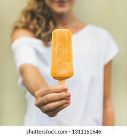 Healthy vegan orange mango citrus ice cream popsicle in hand of young woman with yellow wall at background, square crop. Summer dessert and cheerful summer mood concept - Powered by Shutterstock