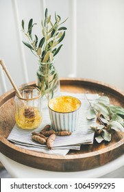 Healthy vegan turmeric latte or golden milk with honey in cup on wooden tray