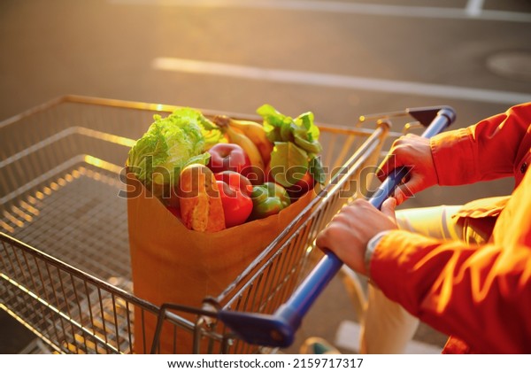 Healthy vegan vegetarian\
food in a paper bag  in the male hands. Young man with shopping bag\
near the car. Consumerism, sale, purchases, shopping, lifestyle\
concept.