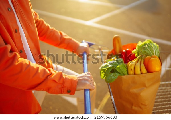 Healthy vegan vegetarian
food in a paper bag  in the male hands. Young man with shopping bag
near the car. Consumerism, sale, purchases, shopping, lifestyle
concept.