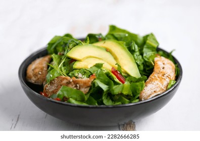 Healthy  vegetable buddha bowl salad with fried chicken and avocado, peppers and leaf lettuce on a white plate. - Shutterstock ID 2282666285