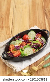 Healthy Vegetable Salad Of Fresh Cherry Tomato, Cucumber, Onion, Purple Cabbage, Carrot, Lettuce, And Lemon Dressing On Black Bowl. Diet Menu Concept