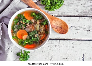 Healthy Vegetable Soup With Kale And Lentils. Overhead View Table Scene On A Rustic White Wood Background.