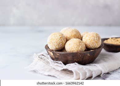 Healthy vegetarian balls with chickpea, peanut butter and coconut in the wooden bowl. Light grey background, selective focus. 