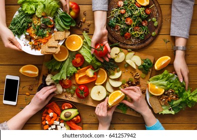 Healthy vegetarian dinner table. Women at home together, eating fruits and vegetables, top view, flat lay, crop
