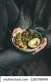 Healthy Vegetarian Dinner. Woman In Jeans And Warm Sweater Holding Buddha Bowl With Fresh Salad, Avocado Half, Grains, Beans, Roasted Vegetables In Hands. Superfood, Clean Eating, Dieting Food Concept