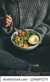 Healthy Vegetarian Dinner. Woman In Jeans And Warm Sweater Eating Fresh Salad, Avocado Half, Grains, Beans, Roasted Vegetables From Buddha Bowl. Superfood, Clean Eating, Dieting Food Concept