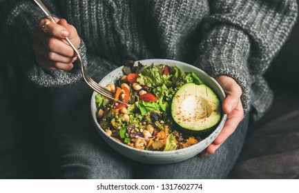 Healthy vegetarian dinner. Woman in jeans and warm sweater holding bowl with fresh salad, avocado, grains, beans, roasted vegetables, close-up. Superfood, clean eating, vegan, dieting food concept - Shutterstock ID 1317602774