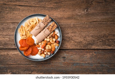 Healthy, Vitamin-rich Snacks In A Plate On A Wooden Background. Granola Bar, Assortment Of Nuts And Dried Fruits.