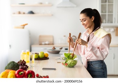 Healthy Weight Loss Concept. Portrait Of Positive Smiling Female Maid Making Vegetarian Salad Standing In Kitchen. Happy Young Woman Mixing Salad In Glass Bowl, Cooking Dinner, Free Copy Space - Powered by Shutterstock