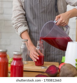 Healthy, weight loss food concept. Woman in linen apron pouring beet detox juice into bottle at home - Powered by Shutterstock