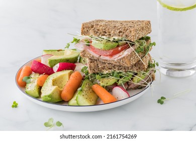 A Healthy Whole Grain Sandwich With Fresh Cut Vegetables And A Glass Of Water.