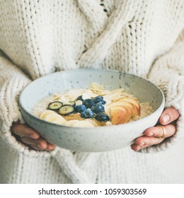 Healthy Winter Breakfast In Bed. Woman In Woolen Sweater Holding Bowl Of Vegan Almond Milk Oatmeal Porridge With Berries Square Crop. Clean Eating, Vegetarian Food Concept